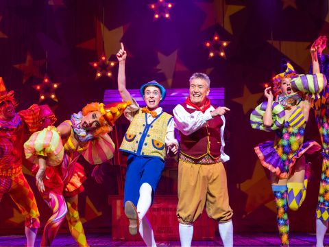 An image of Pinocchio and Geppetto on stage with dancers behind them